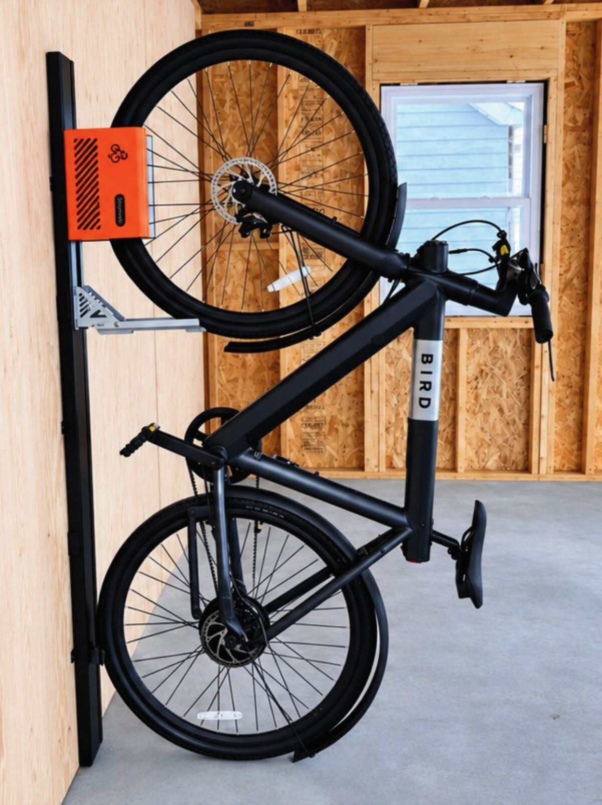 B-Cycle Box orange bike lift on a black rail inside a shed